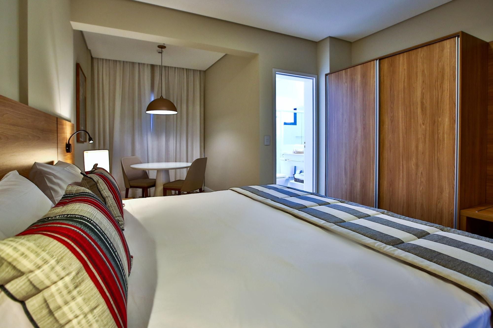 A hotel room with a large bed, a desk, and a wardrobe.