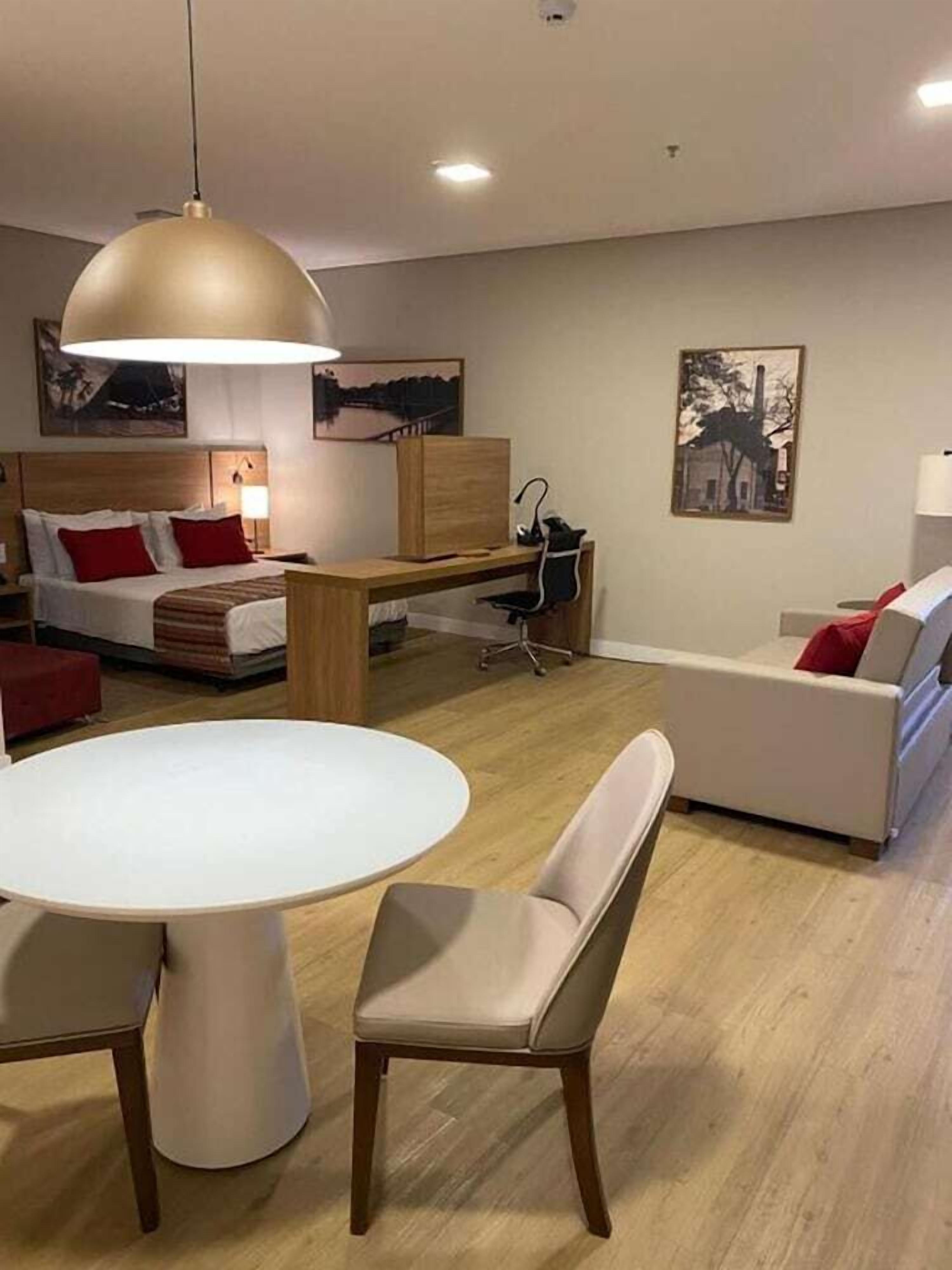 Une chambre d’hôtel moderne équipée d’un lit, d’un bureau, d’une chaise, d’une table à manger et d’un canapé.