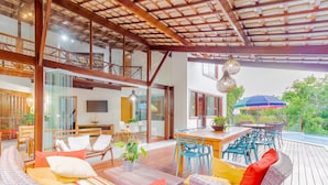 A spacious outdoor deck with wicker furniture, a dining area, and a view of the surrounding greenery.