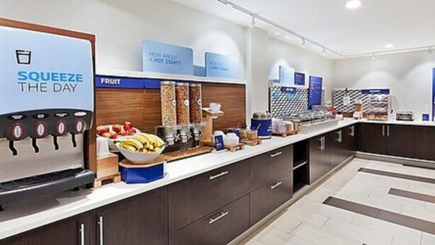 A modern kitchen with a fruit bar, a beverage dispenser, and a coffee machine. - Holiday Inn Express and Suites Griffin by IHG (Griffin)