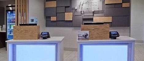 A hotel reception area with two reception desks, each equipped with a digital display and a card reader. A sign above the desks reads "Hotel Express."