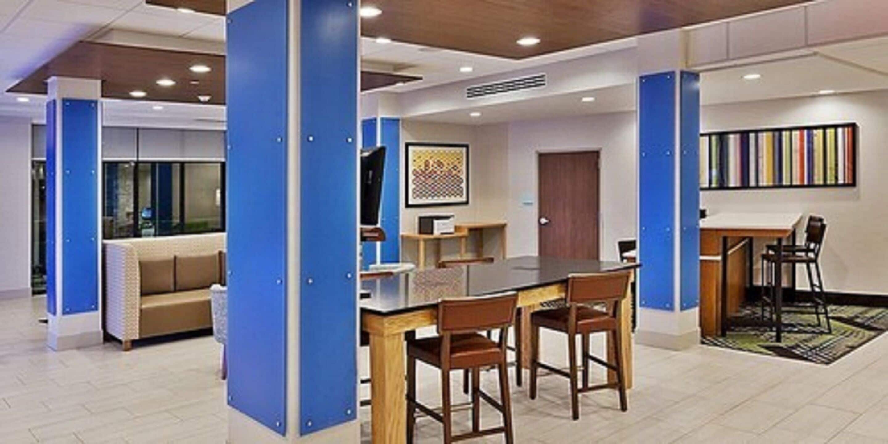 Un vestíbulo de hotel moderno con un área de comedor central, un sofá y una estantería.