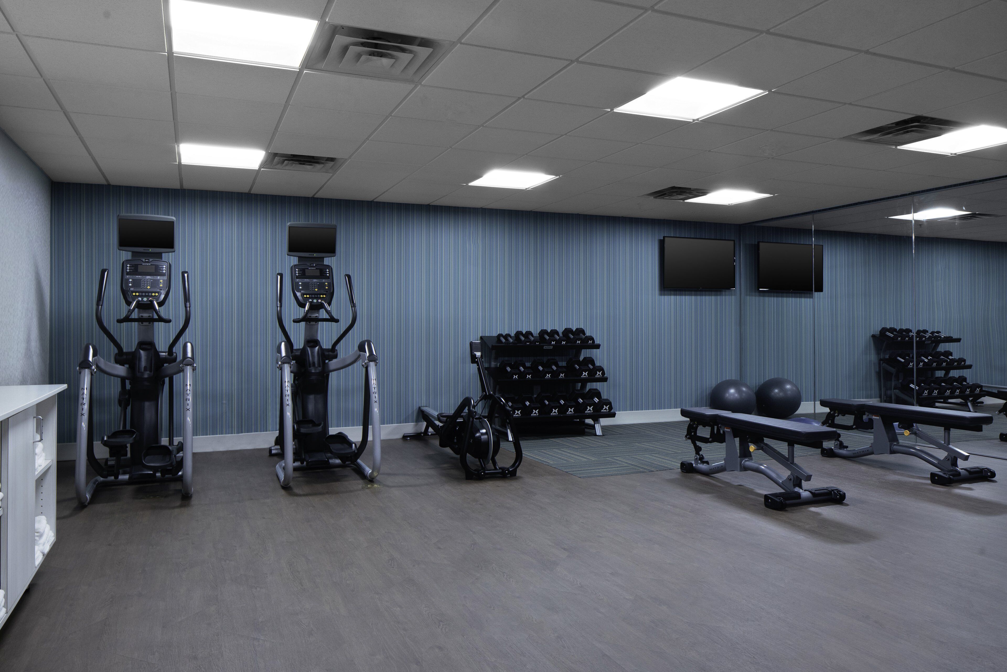 Un gimnasio con cintas de correr, elípticas, mancuernas y pelotas de ejercicio.