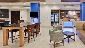 A modern hotel lobby with a dining area, a reception desk, and a seating area. - Holiday Inn Express and Suites Griffin by IHG (Griffin)