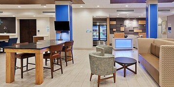 Un moderno vestíbulo de hotel con zona de comedor, recepción y área de descanso.