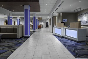 Un vestíbulo de hotel con mostrador de recepción, zona de estar y alfombra estampada.