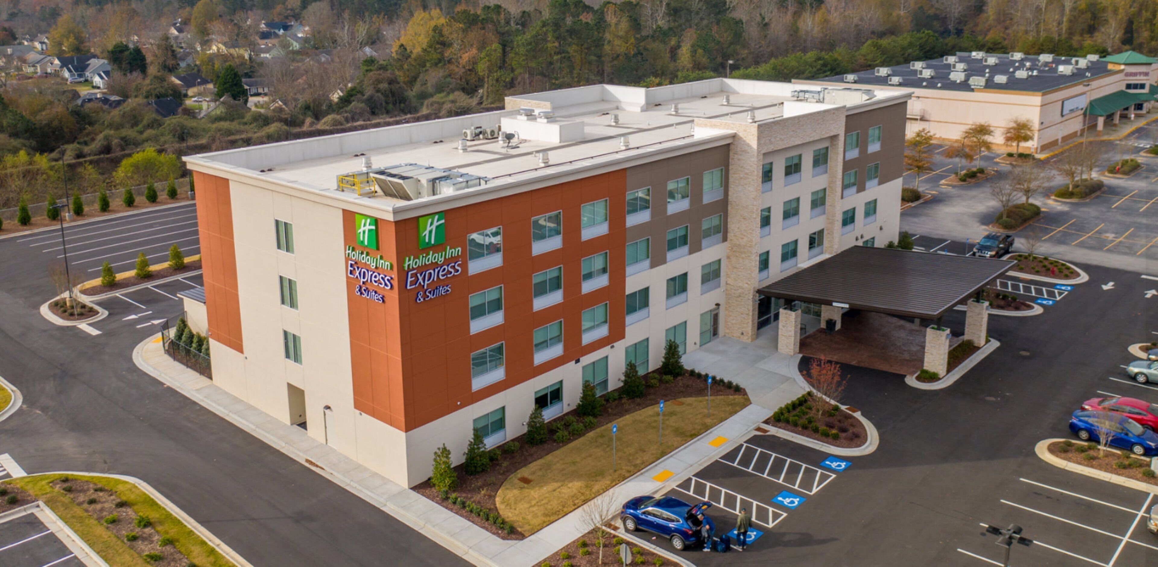 Ein Holiday Inn Express & Suites Hotel mit modernem Design, inklusive Parkplatz und überdachter Zufahrt.