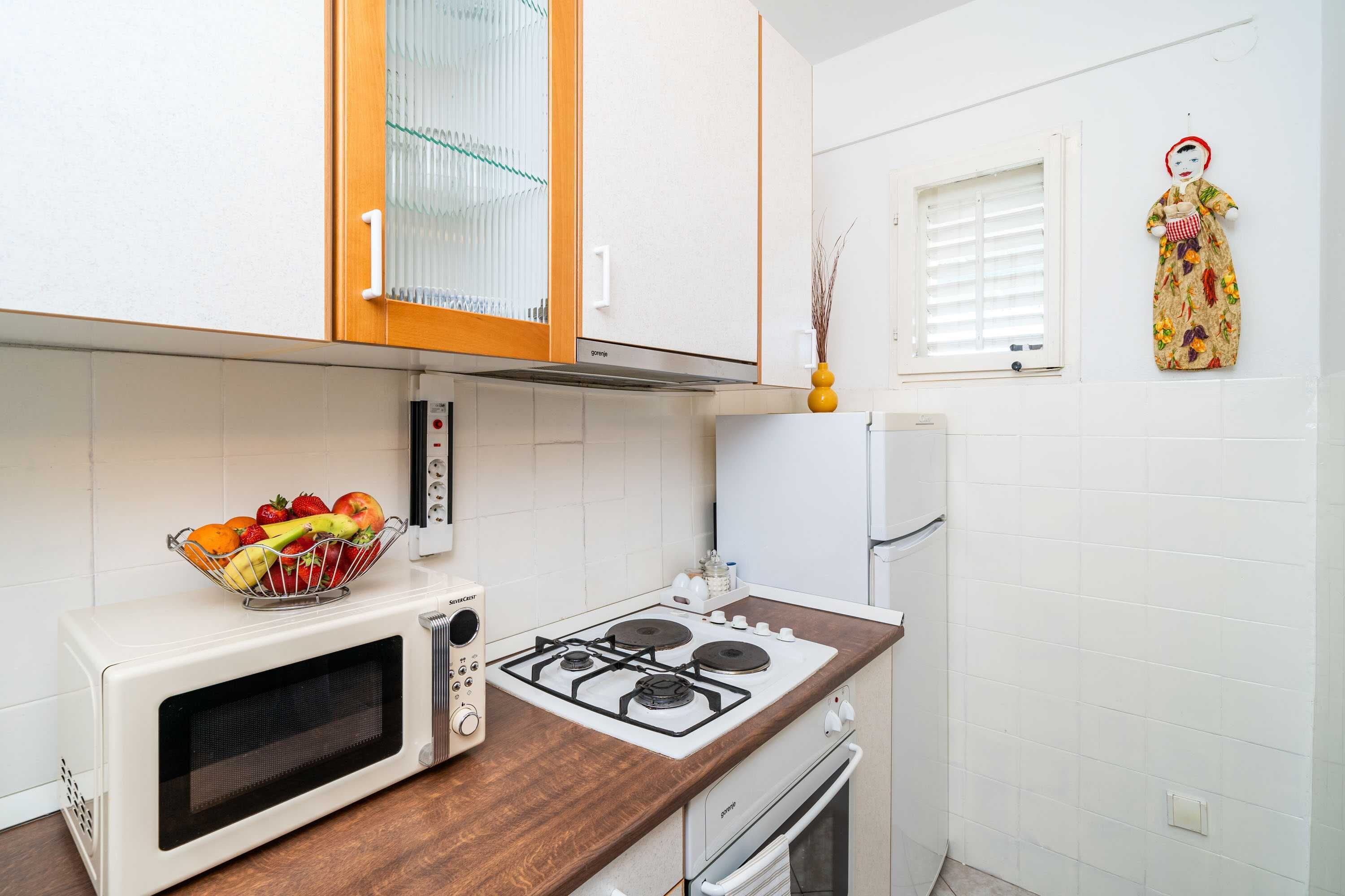 A kitchen with a microwave, stove, and a fruit bowl on the counter.