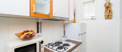 A kitchen with a microwave, stove, and a fruit bowl on the counter.
