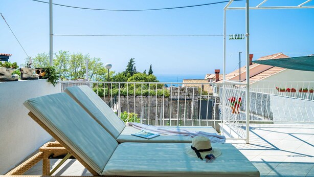 A balcony with a lounge chair, a hat, and a magazine. - Apartments Nico (Dubrovnik)