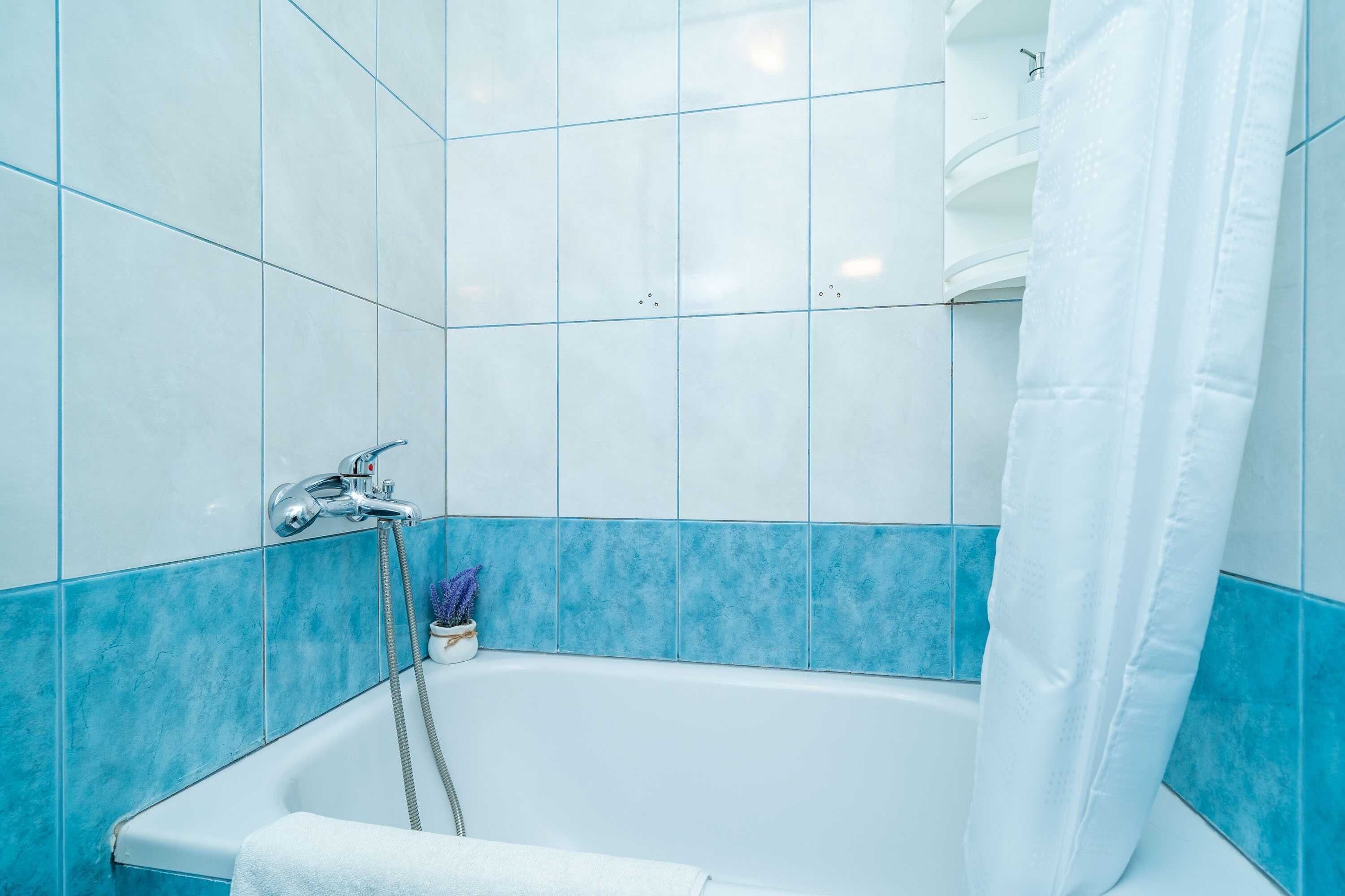 A bathroom with a bathtub, a shower curtain, and a towel rack.
