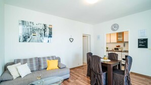 A living room with a sofa, a glass coffee table, and a dining area with chairs and a table. - Apartments Nico (Dubrovnik)