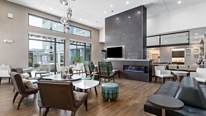 A modern lounge area with a fireplace, comfortable seating, and large windows offering views of the outside. - Residence Inn by Marriott Port Arthur (Port Arthur)