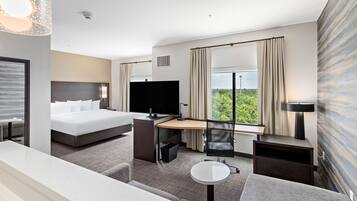 A modern hotel room with a bed, desk, chair, and a small table.