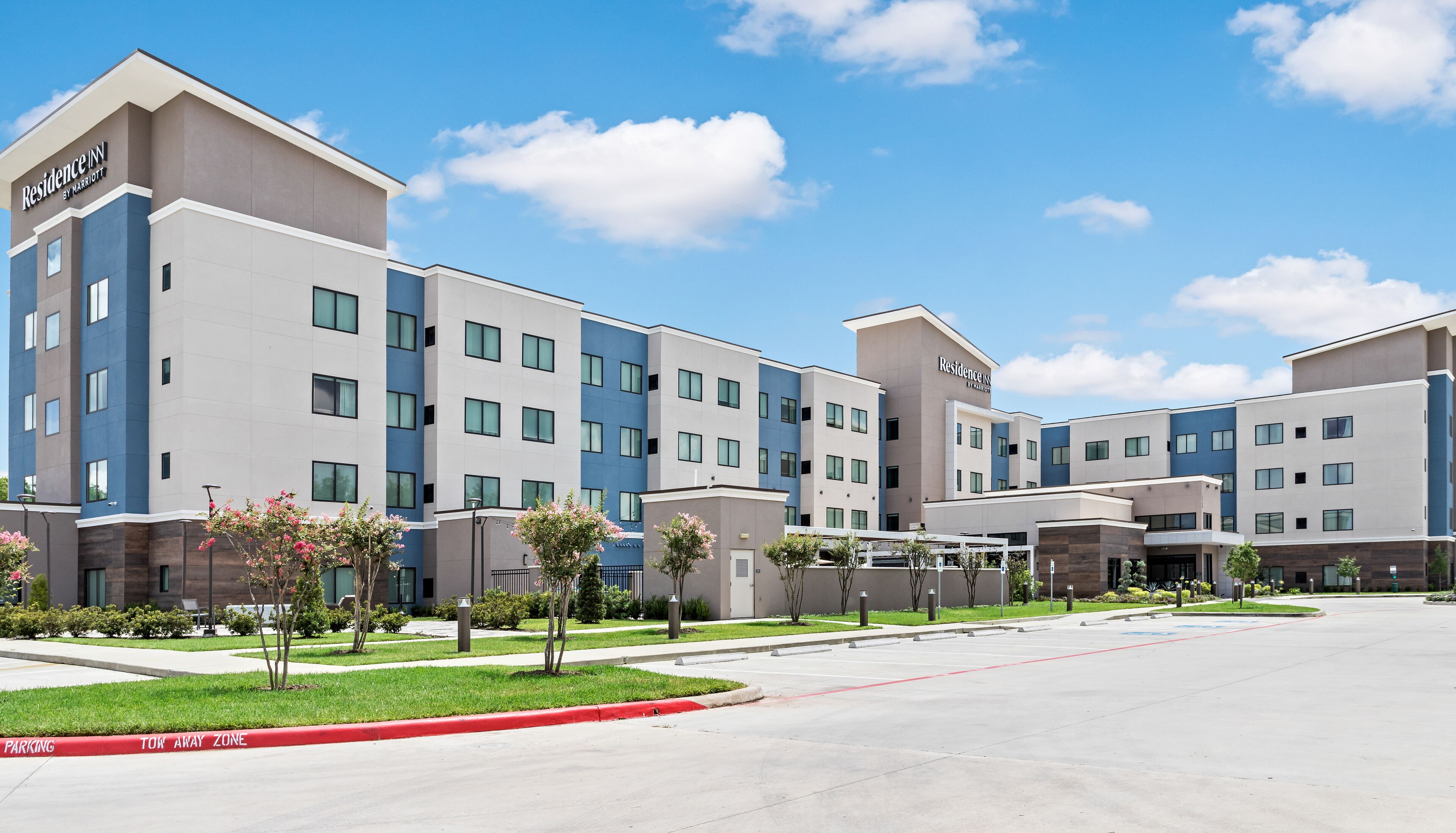 A multi-story hotel with a modern design, featuring a flat roof and a mix of blue and beige exterior colors.