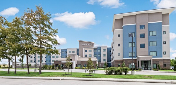 A modern hotel with multiple floors, a prominent entrance, and a landscaped front yard with trees. - Residence Inn by Marriott Port Arthur (Port Arthur)