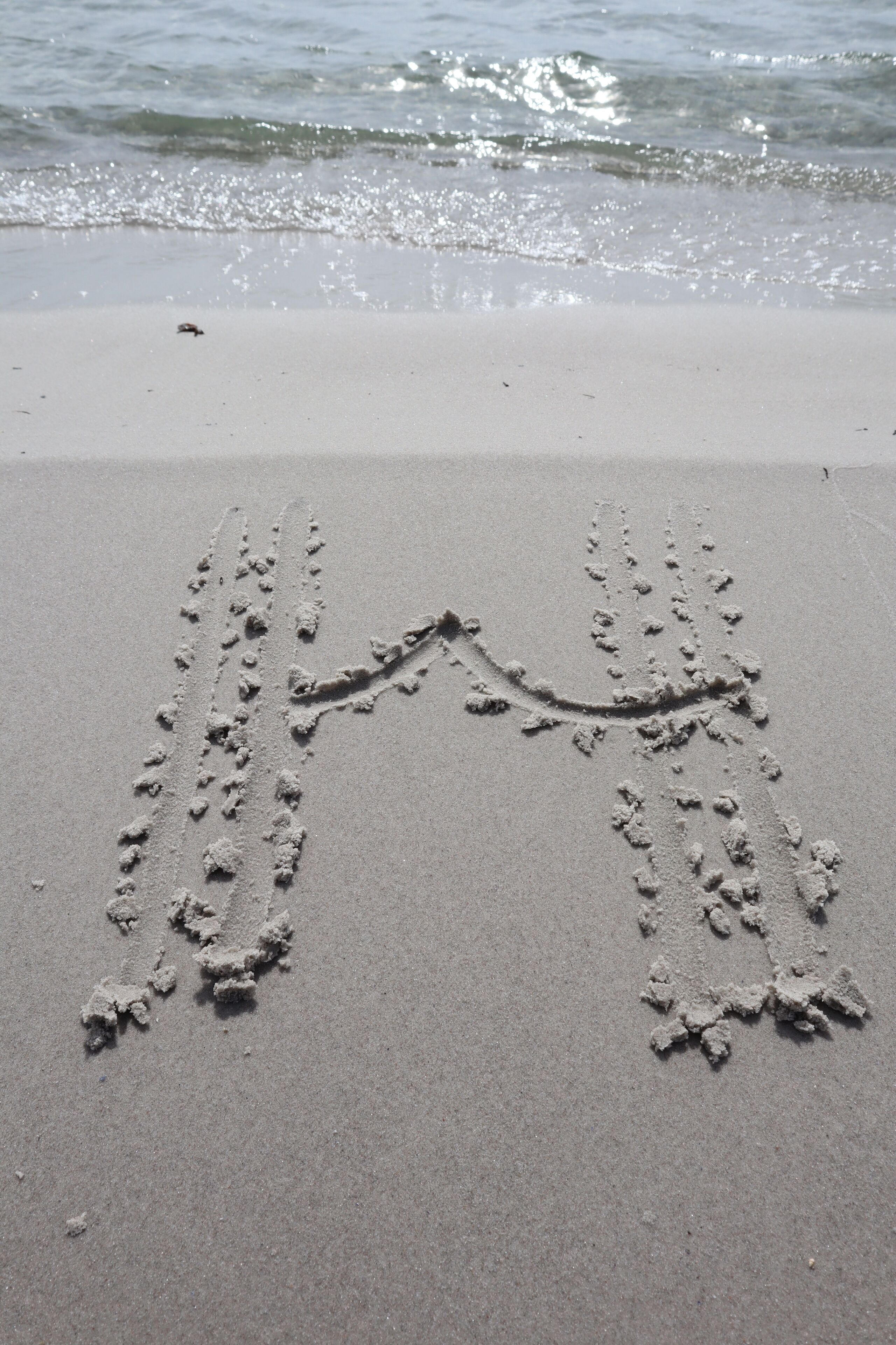 A sandy beach with footprints leading to the water.