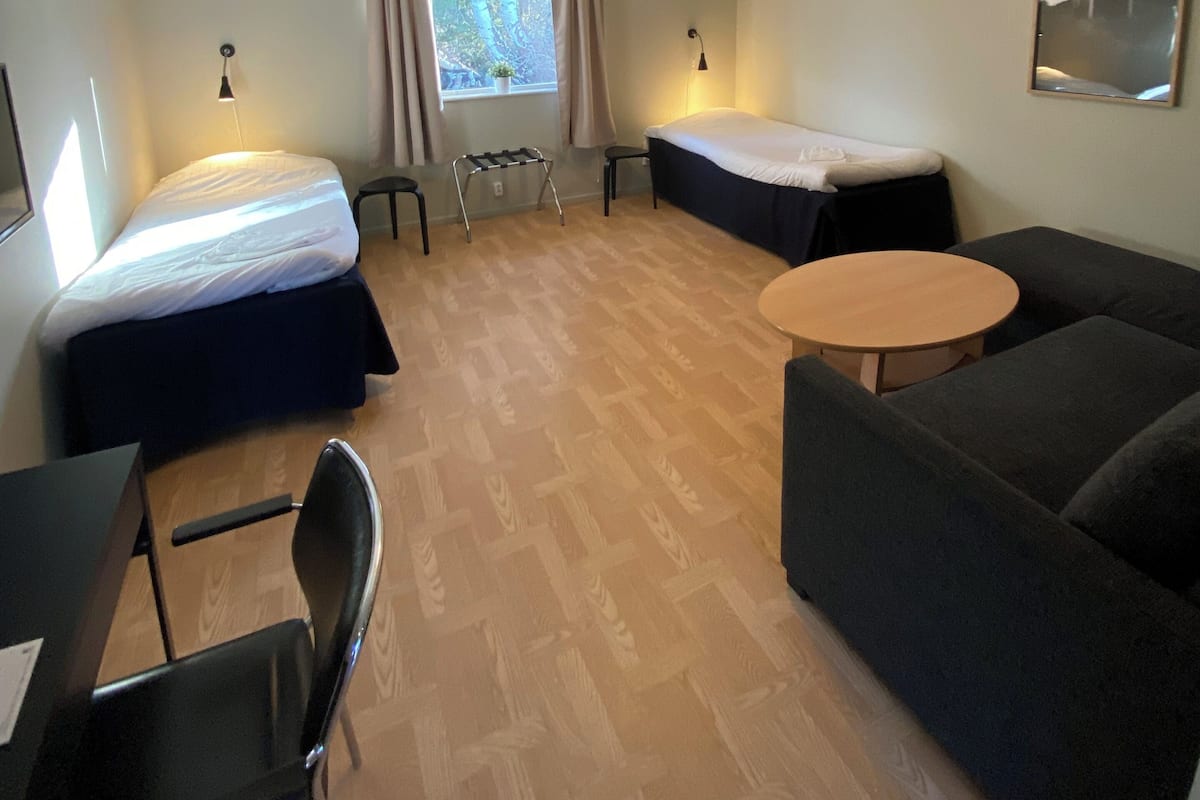 Une chambre d’hôtel avec un lit, un canapé, une petite table, un bureau et une chaise.
