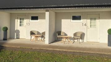 Een gebouw met twee verdiepingen, met de nummers 13 en 14, elk met een klein raam en een deur.