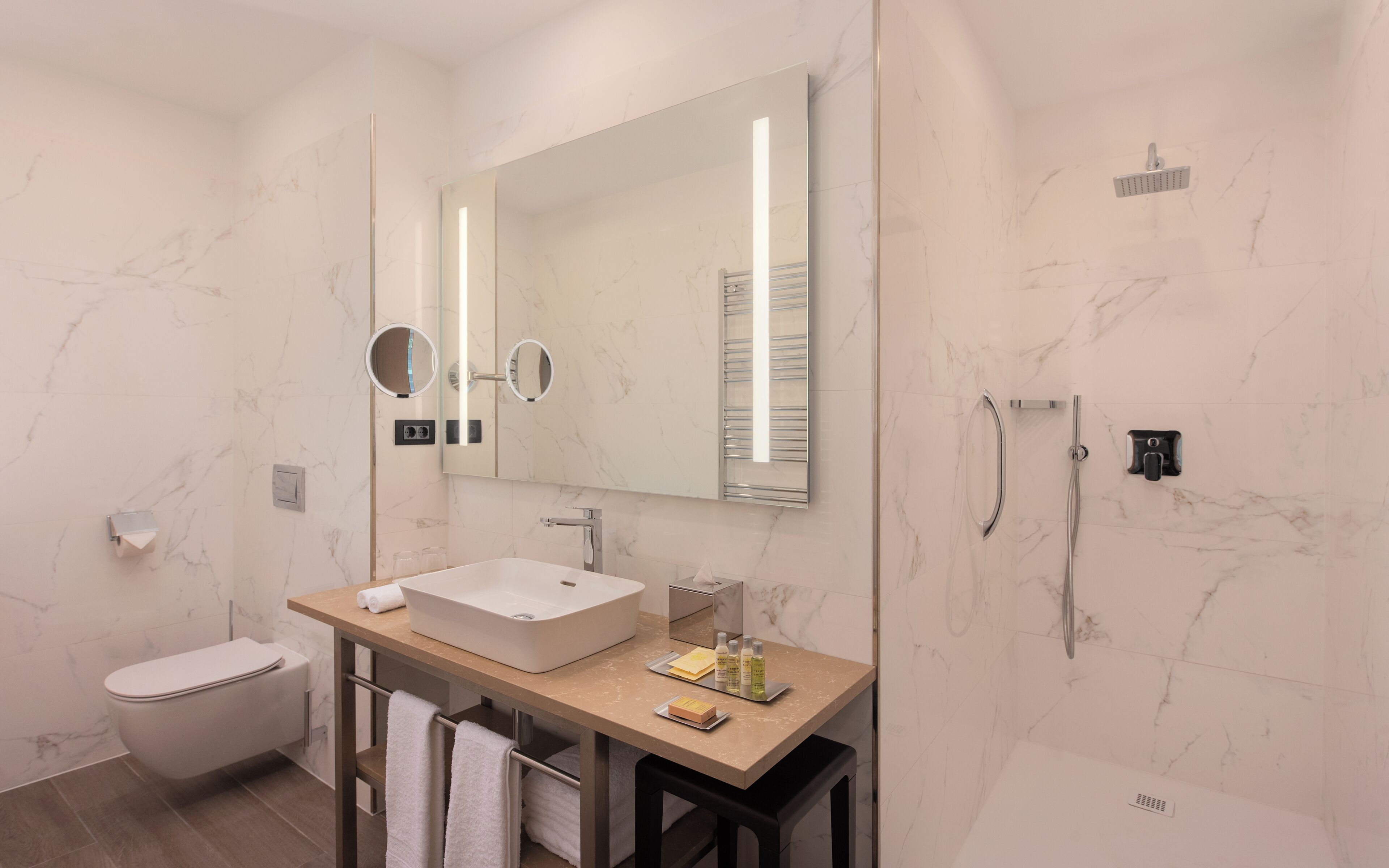 Un baño moderno con un espejo grande, una bañera, un inodoro y una ducha.