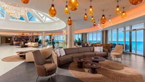 A spacious lobby with a large seating area, a bar, and a pool. - Hilton Rijeka Costabella Beach Resort & Spa (Rijeka)