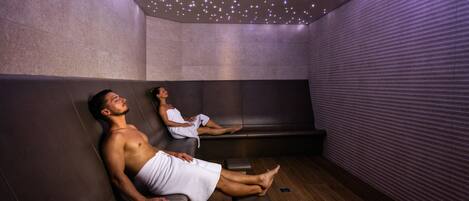 A room with two massage chairs, a wooden floor, and a ceiling with small lights.