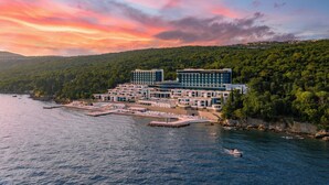 A coastal hotel with multiple buildings, a marina, and a forested hillside. - Hilton Rijeka Costabella Beach Resort & Spa (Rijeka)