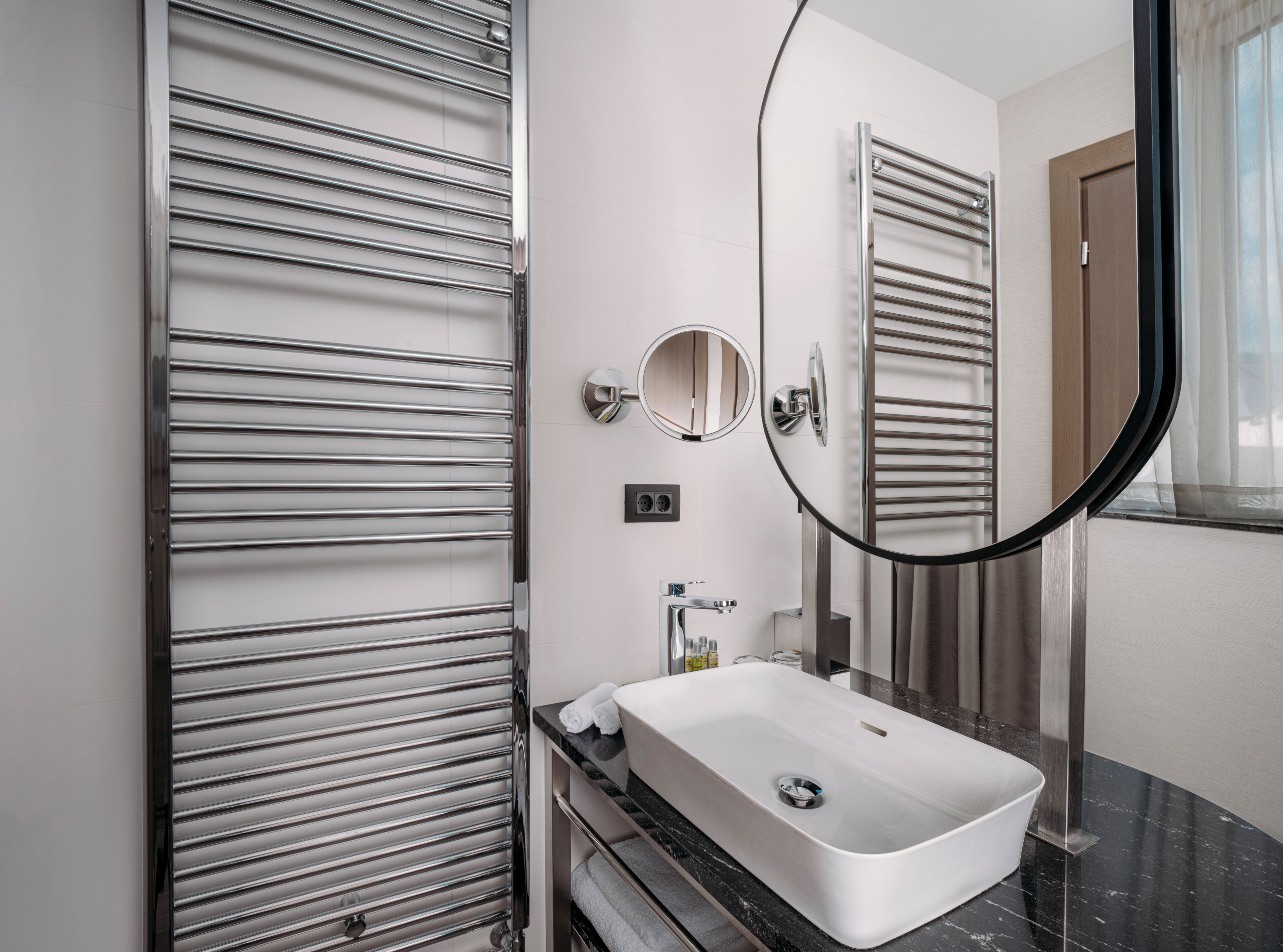 Un baño moderno con un lavamanos rectangular, un perchero, un espejo y una puerta.