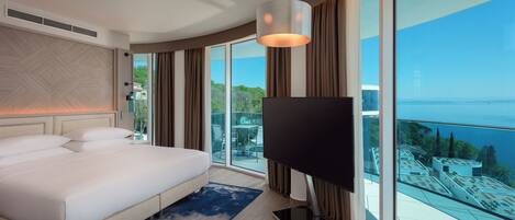 Una habitación de hotel moderna con una cama grande, un televisor de pantalla plana y un balcón con vistas a la ciudad.