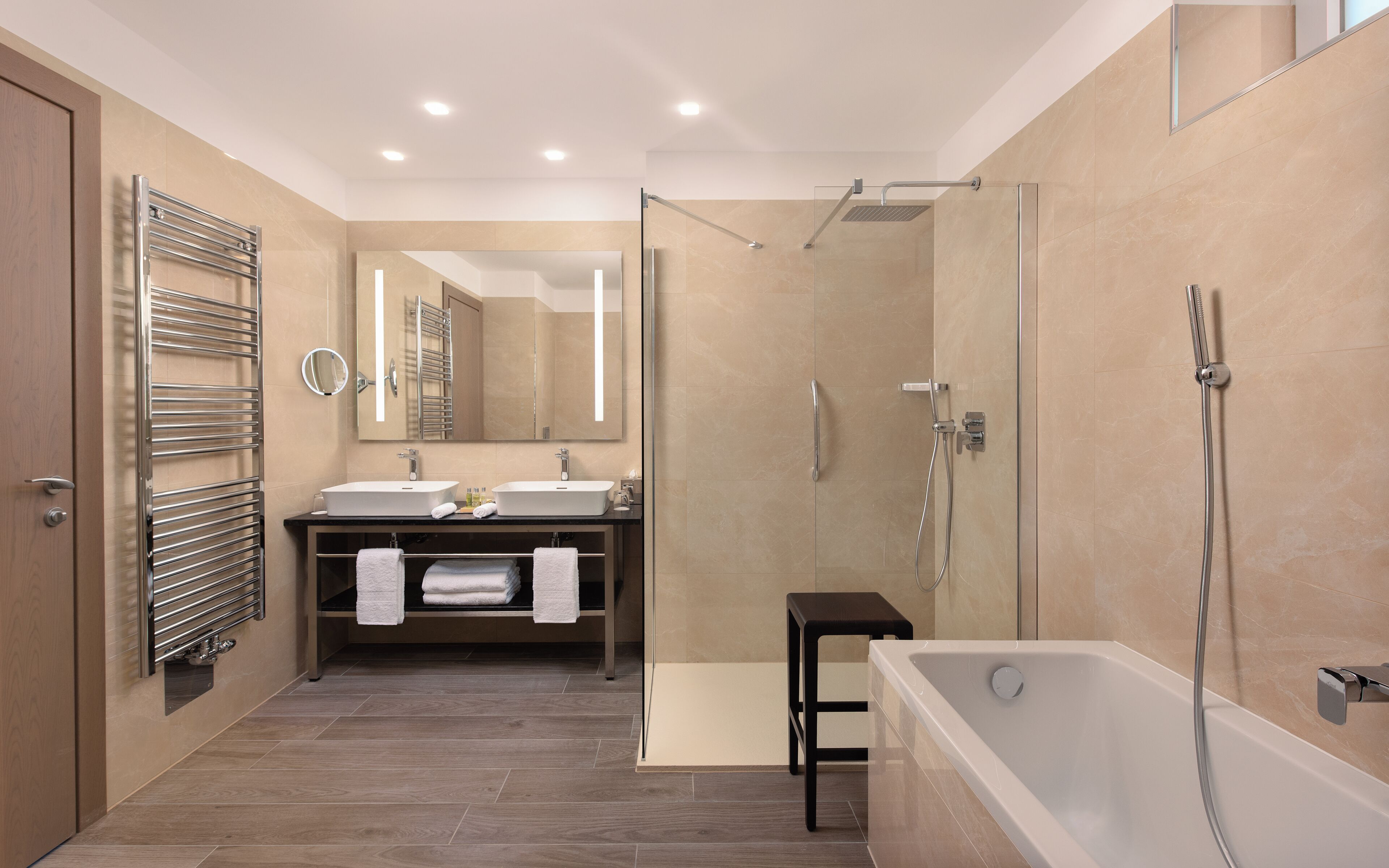 Un baño moderno con cabina de ducha de vidrio, bañera y tocador doble.