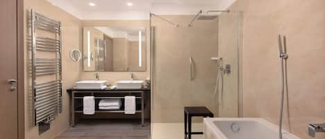 A modern bathroom with a glass shower enclosure, a bathtub, and a vanity with two sinks.
