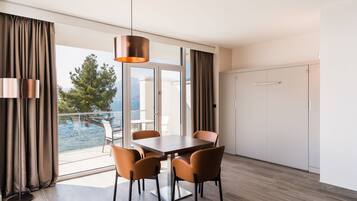 Un comedor moderno con una mesa y sillas, una lámpara colgante y vista al mar a través de grandes ventanales.