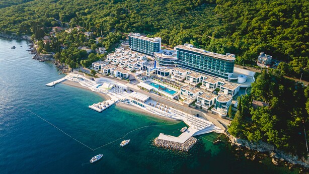 An aerial view of a coastal hotel with multiple buildings, a swimming pool, and a dock with boats. - Hilton Rijeka Costabella Beach Resort & Spa (Rijeka)