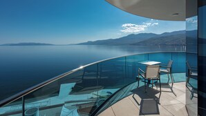 A balcony with a glass railing overlooking a body of water and distant mountains. - Hilton Rijeka Costabella Beach Resort & Spa (Rijeka)