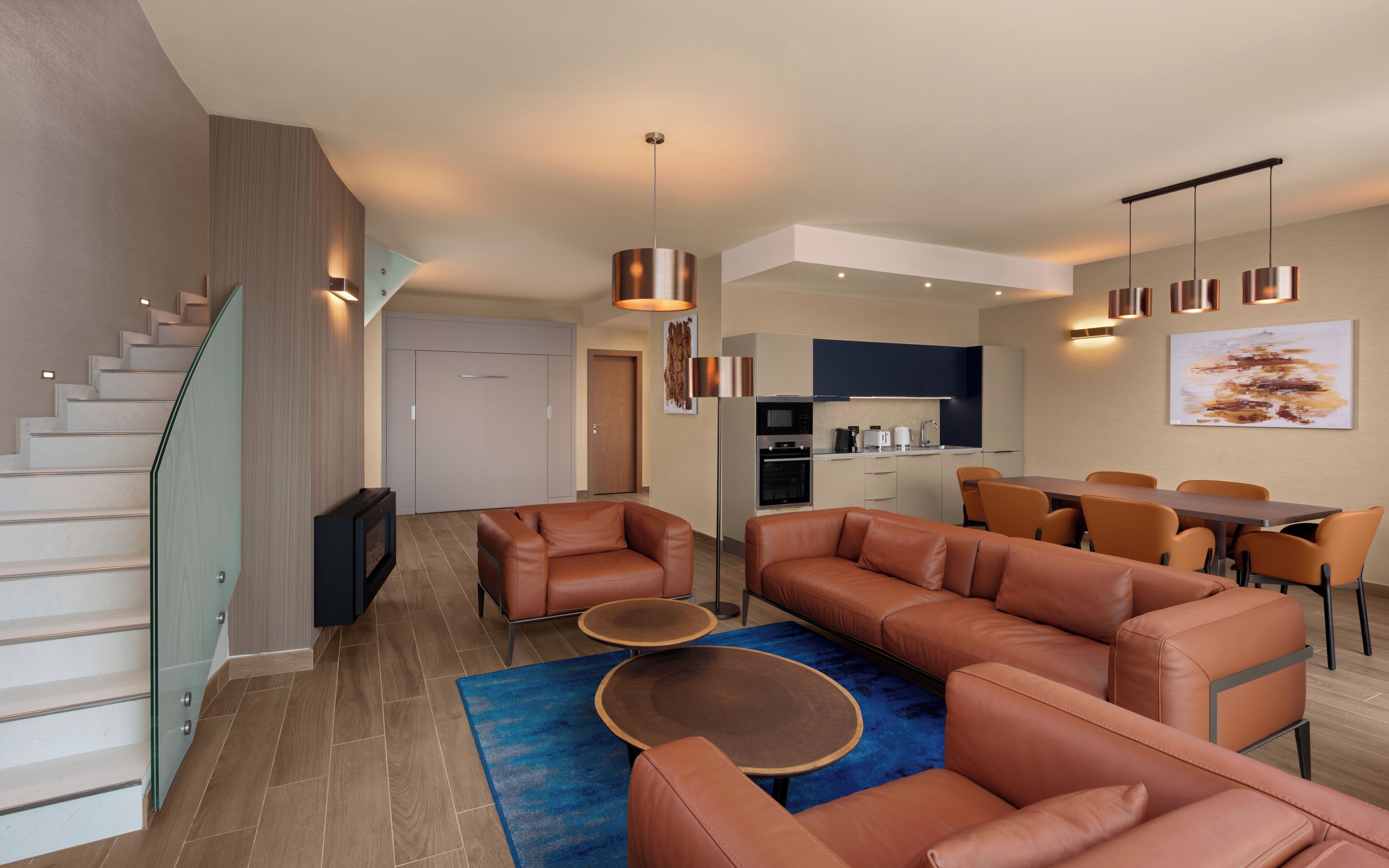 A modern apartment with a staircase, living room, dining area, and kitchen.