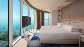 A hotel room with a large bed, a TV, and a view of the sea. - Hilton Rijeka Costabella Beach Resort & Spa (Rijeka)