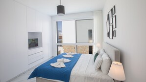 A modern hotel room with a large bed, a TV, a window with a city view, and a wall-mounted lamp. - Villa Lilia, Fabulous, New, 4BDR Protaras Villa with Pool, Close to Fig Tree Bay (Protaras)