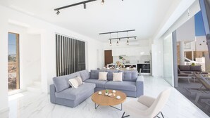 A modern living room with a sectional sofa, a round coffee table, and a minimalist design. - Villa Lilia, Fabulous, New, 4BDR Protaras Villa with Pool, Close to Fig Tree Bay (Protaras)