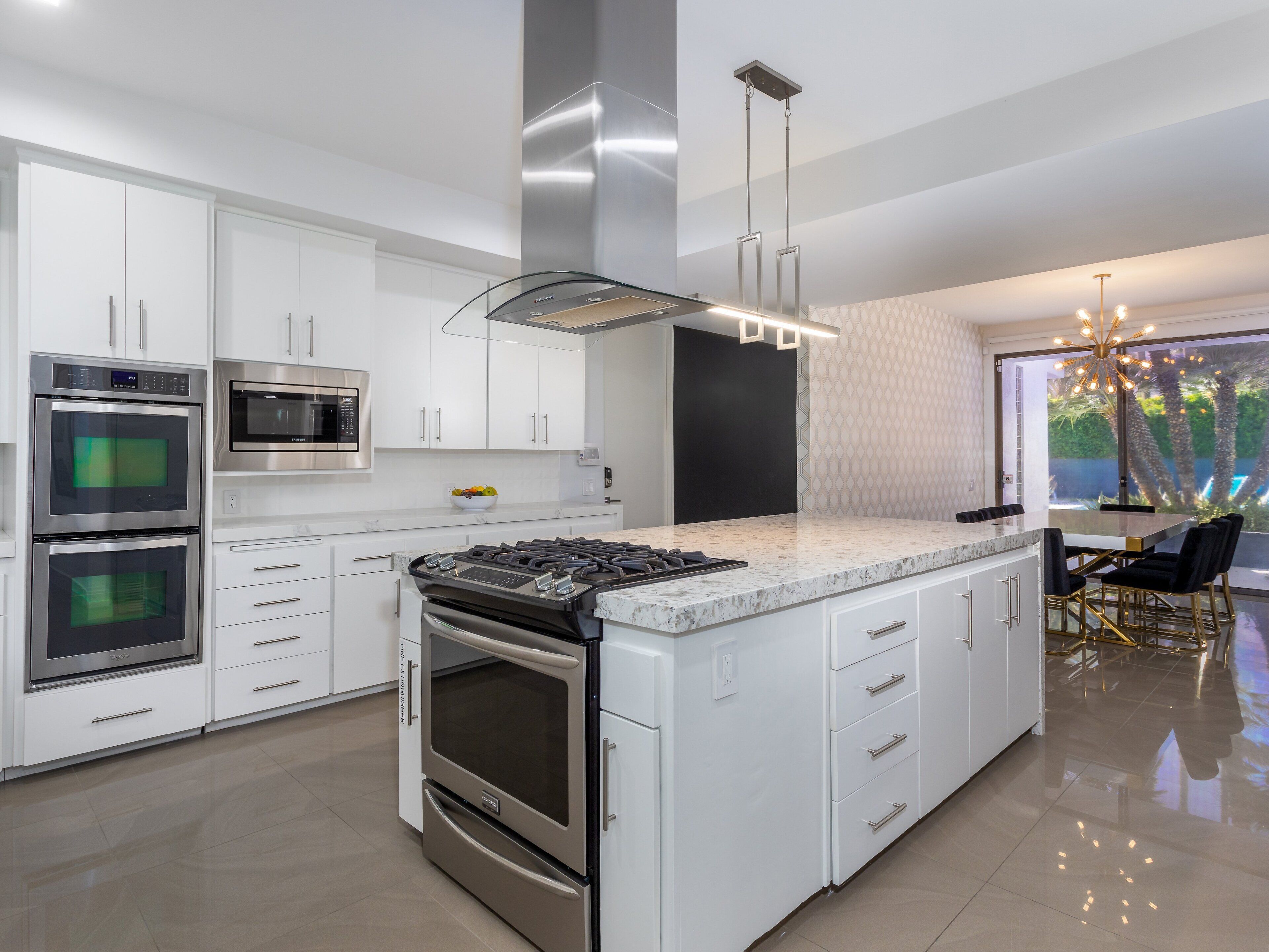 A modern kitchen with stainless steel appliances, white cabinetry, and a large island with seating.