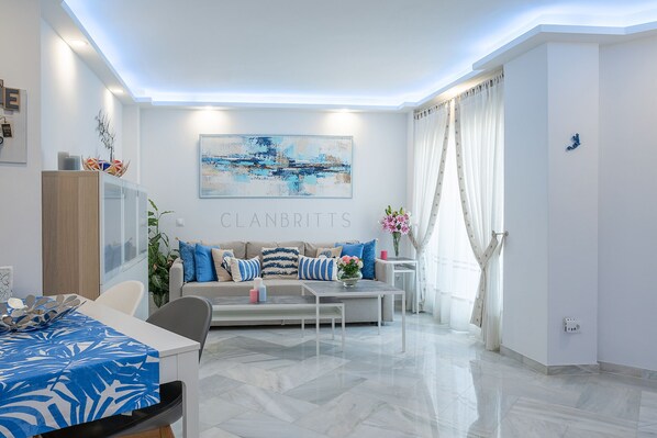 A modern living room with a sofa, coffee table, and dining area.