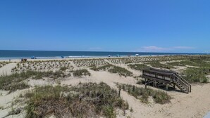 Una playa con un paseo marítimo de madera y dunas.