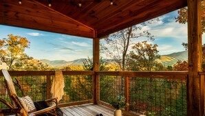 Una terraza de madera con vistas a follaje otoñal y montañas.