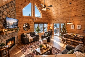 Ein gemütliches Blockhaus-Interieur mit Kamin, Ledersofas, einem Essbereich und einem Weihnachtsbaum.