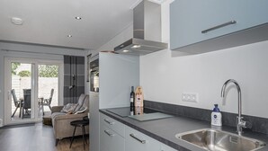 Et moderne køkken med grå skabe, en stålvask og en indbygget ovn.