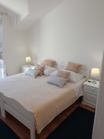 Un dormitorio ordenado con cama, mesitas de noche y lámparas.