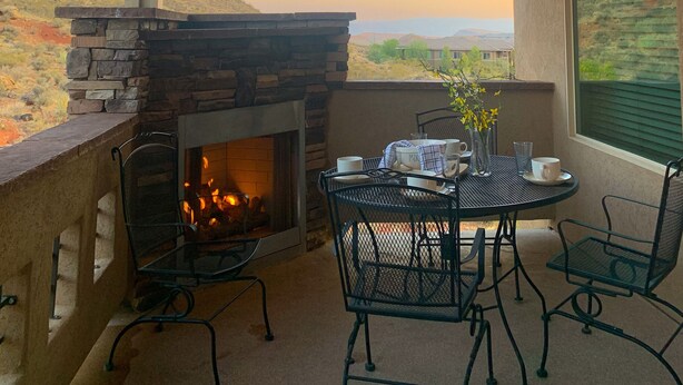 A patio with a stone fireplace, outdoor seating, and a view of the landscape. - Zions Gateway Escape (Hurricane)