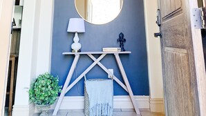 A foyer with a chandelier, a round mirror, a lamp, a small table, and a plant. - Zions Gateway Escape (Hurricane)
