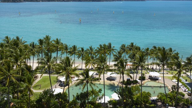 Ein Resort mit Pool, umgeben von Palmen, einem Strand und Blick auf den Ozean.