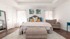 Een slaapkamer met een bed, een bankje, een stoel en een tafel.