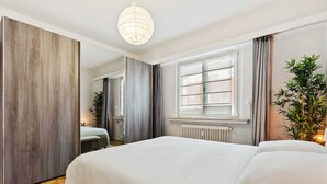 Una camera da letto moderna con un letto grande, un armadio in legno, un termosifone e una finestra con tende.